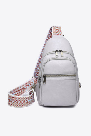 Gray sling bag with geometric strap and multiple zipper pockets