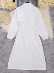 White midi dress with lapel collar, tie waist, and cuffed sleeves.