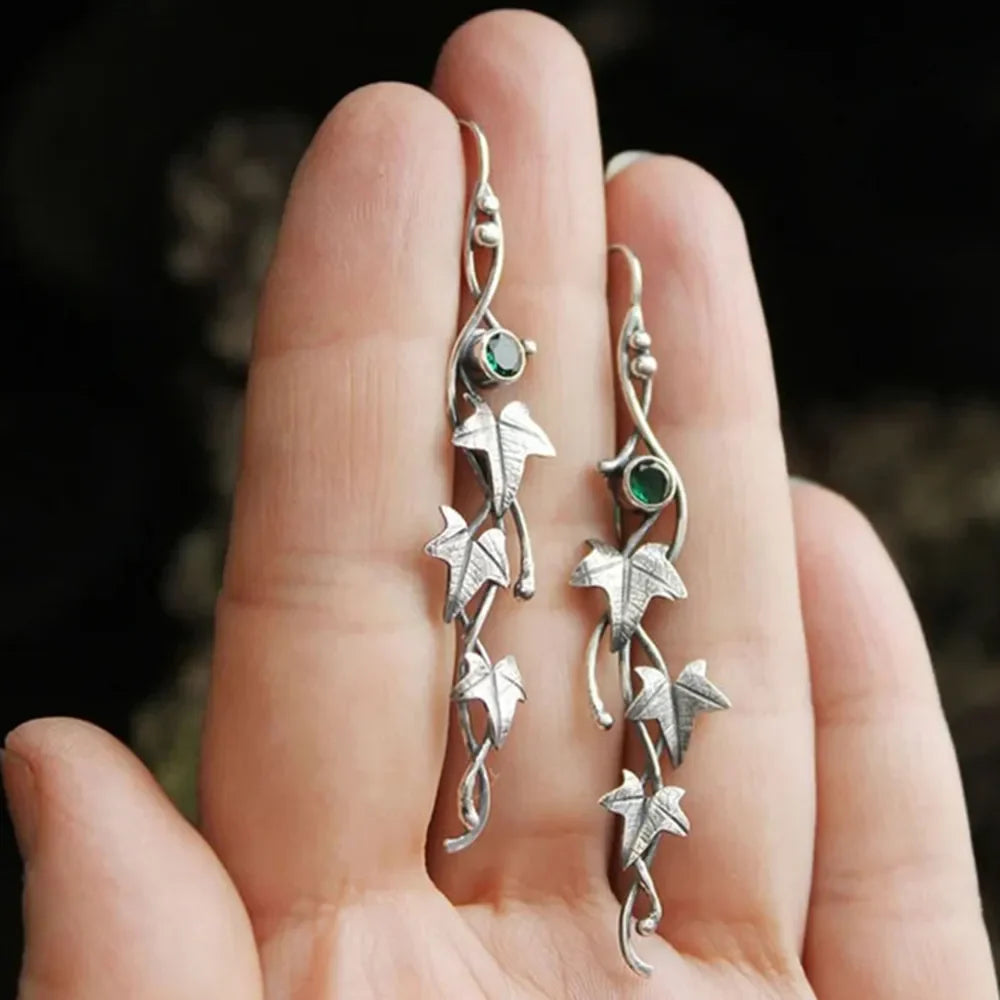 Silver drop earrings with green gemstones and ivy leaf charms.