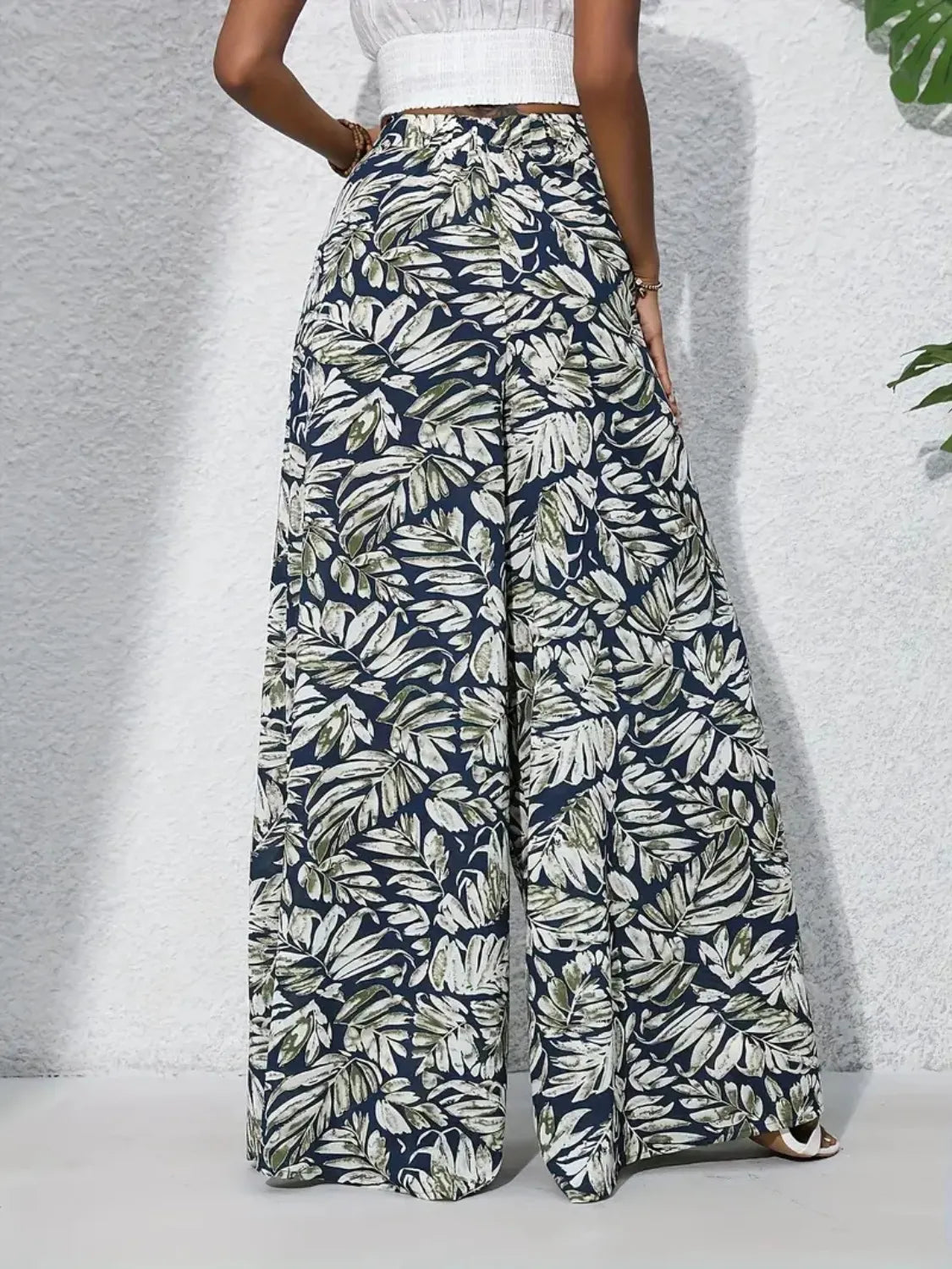 Palazzo trousers with tropical leaf print in navy, green, and white.
