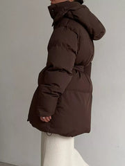 Dark brown belted puffer trench coat with hood, visible detail of cinched waist and drawstring hem.