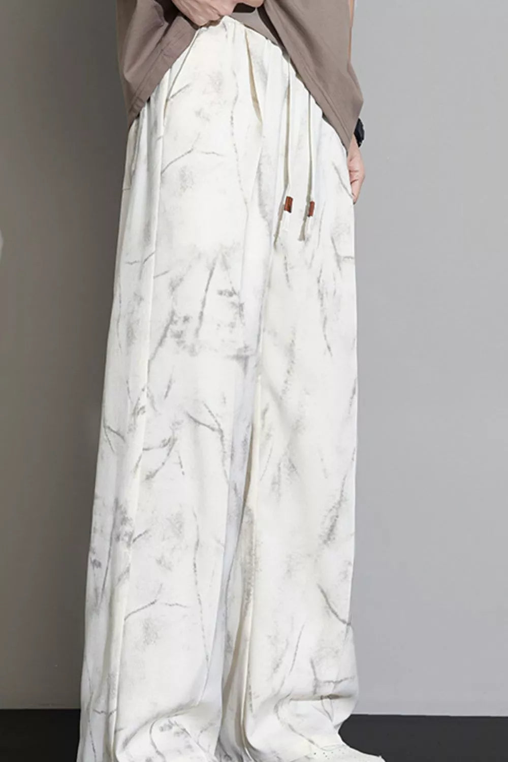 Men's white sweatpants with marbled pattern and drawstring waist.