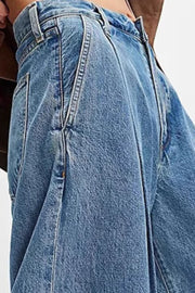 Dusty blue denim pleated wide-leg trousers with buttoned waist and pockets.