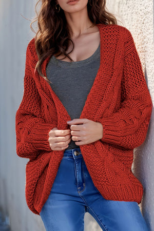 Red cable knit open-front cocoon cardigan with chunky knit texture and relaxed fit.