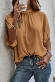 Camel blouse with drapey sleeves and mock neckline, styled with jeans.