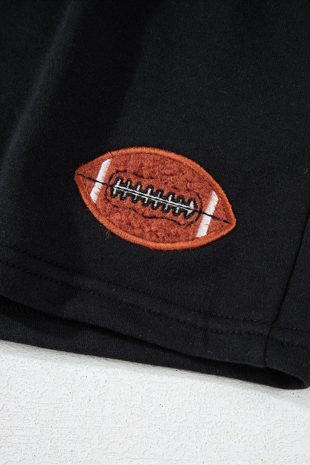 Black cotton sweatshirt with embroidered football detail.