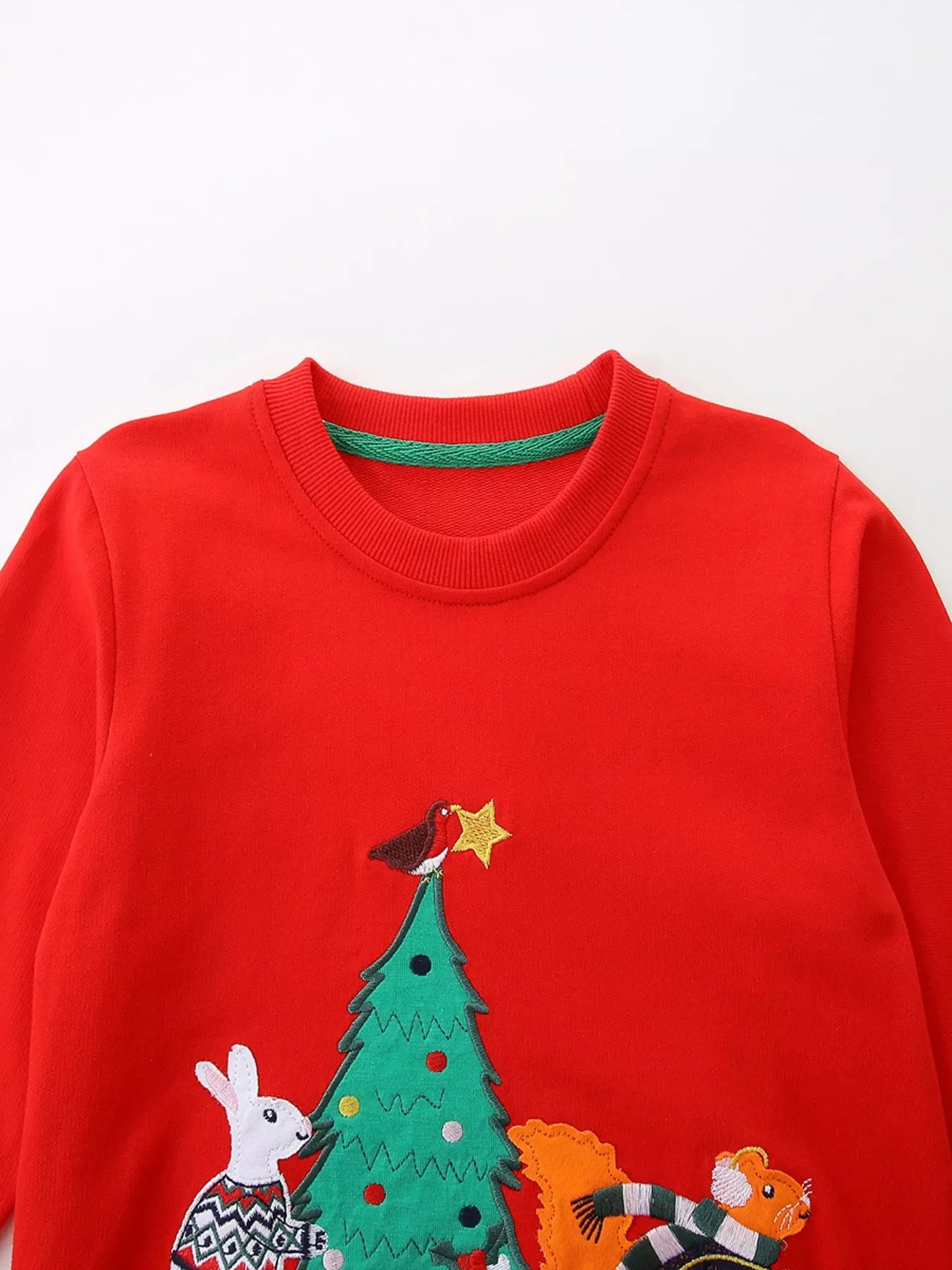 Red cotton crewneck sweatshirt with embroidered holiday scene of a Christmas tree, rabbit, squirrel, and bird.