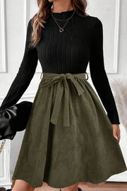Black ribbed mock neck top with olive green A-line skirt and tie belt