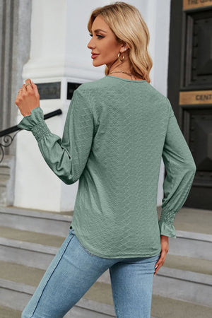Sage green textured V-neck blouse with smocked cuffs and lace trim detail.