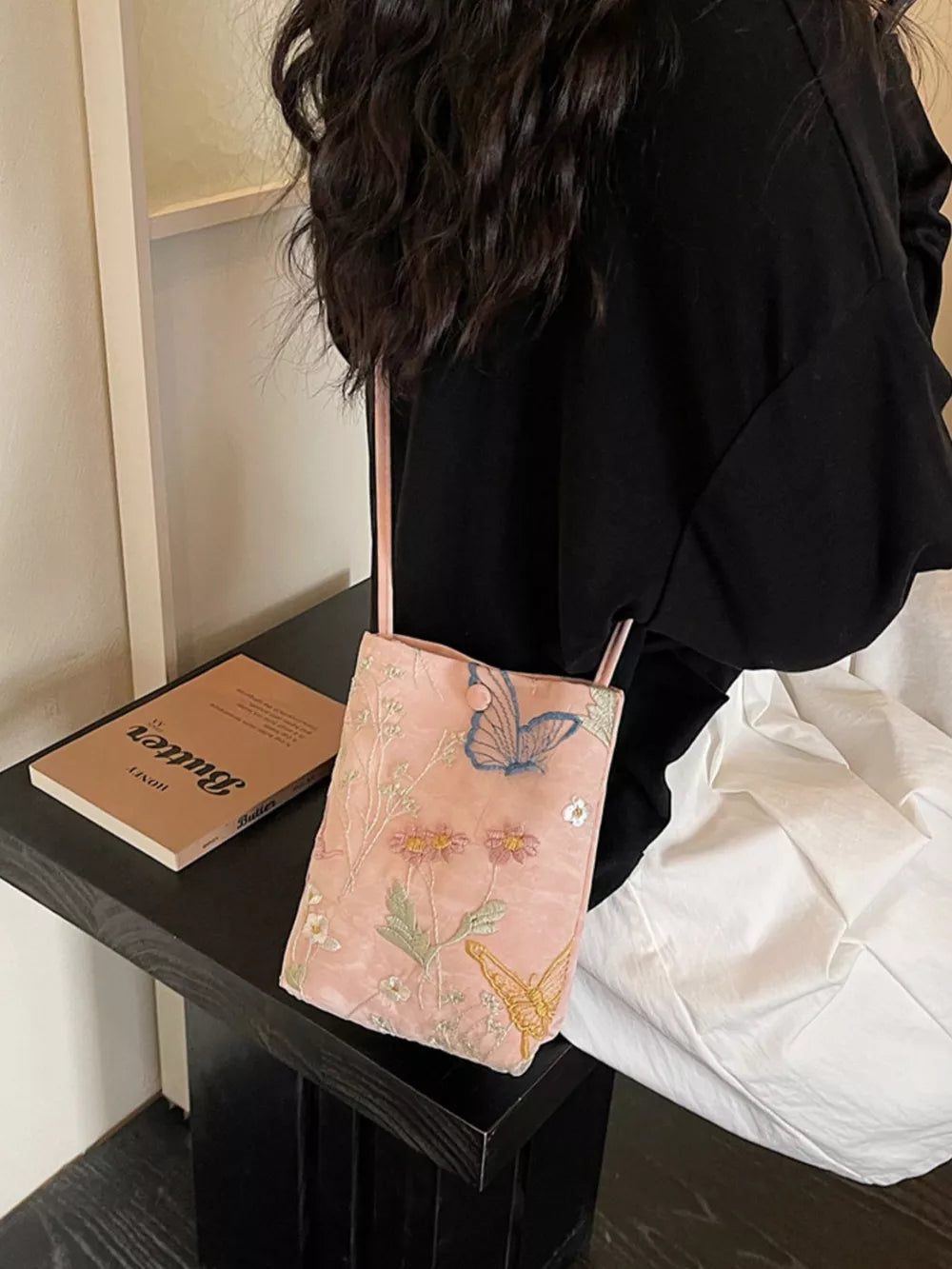 Pink crossbody bag with delicate butterfly and floral embroidery.