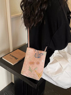 Pink crossbody bag with delicate butterfly and floral embroidery.