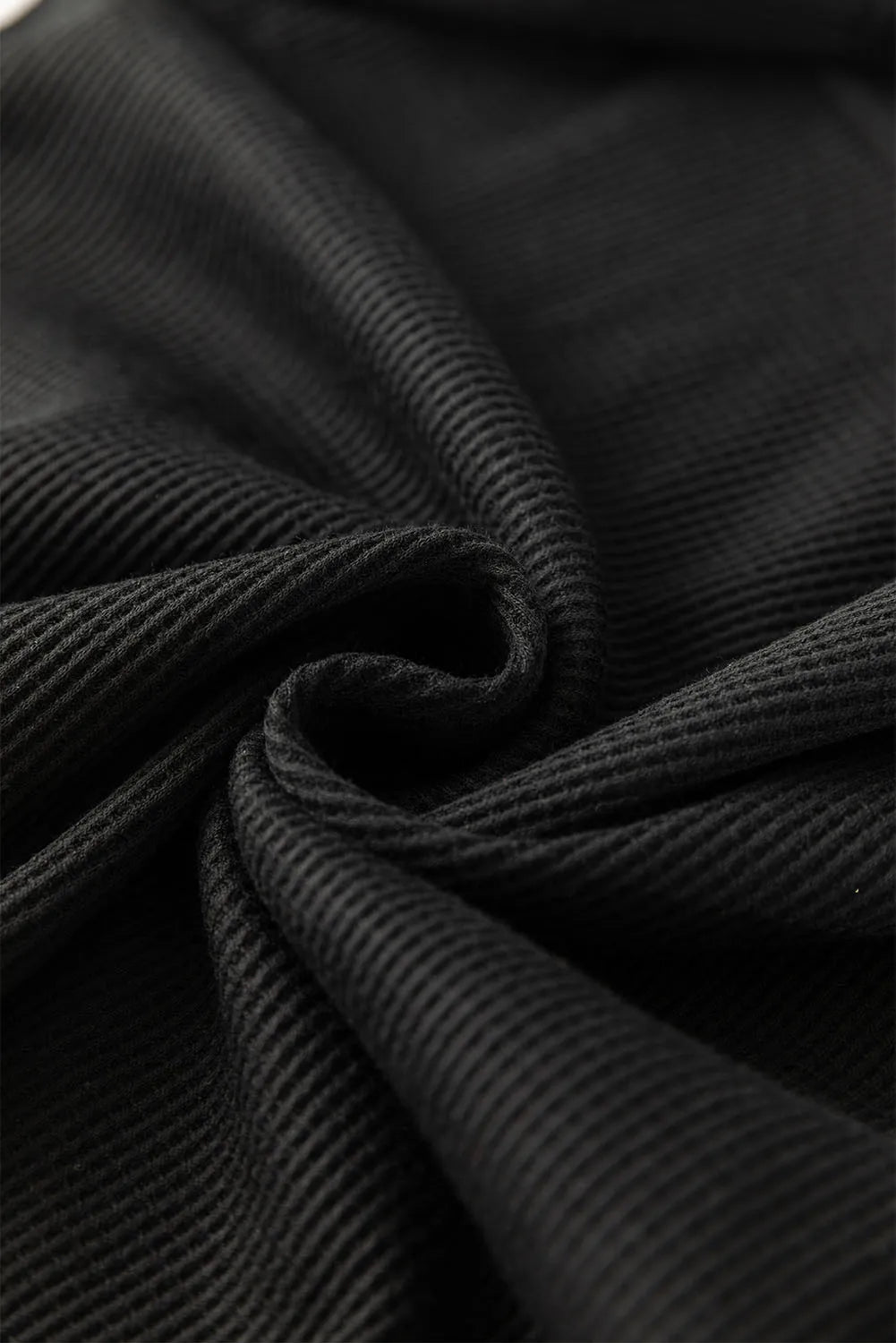 Black ribbed knit fabric detail, showing texture and drape