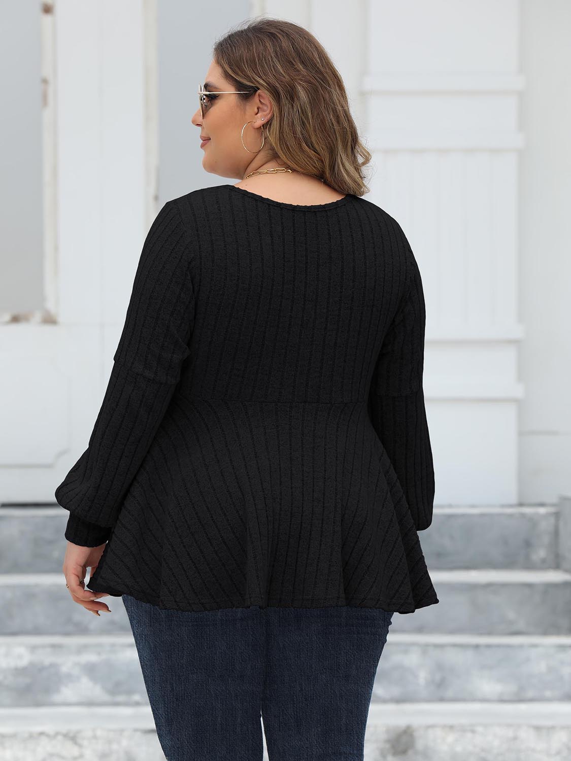 Black ribbed peplum blouse with blouson sleeves and a flared hem.