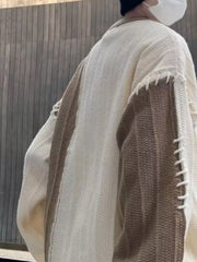 Oversized white sweater with khaki color block sleeves and decorative stitching detail.
