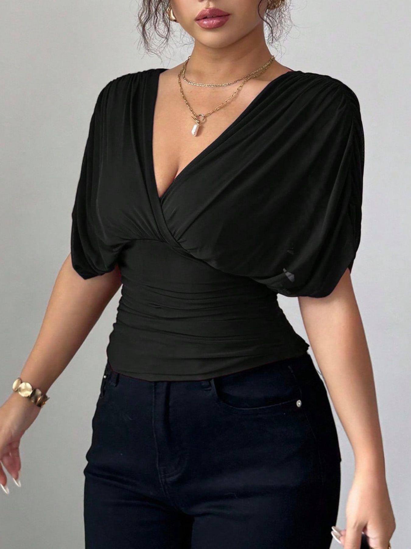 Black ruched surplice dolman sleeve top with deep V-neck and elastane fabric.