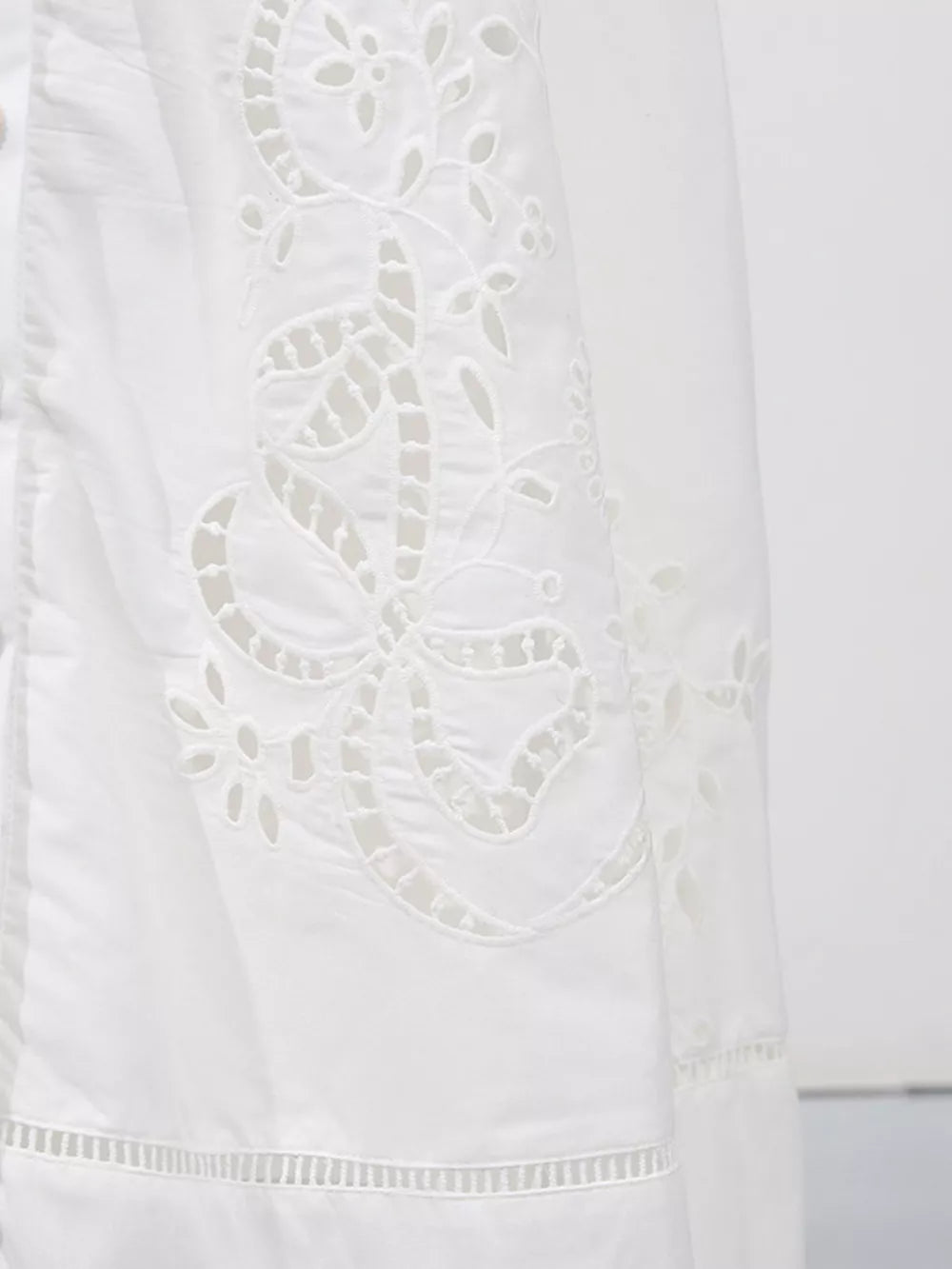 White midi dress with elegant eyelet embroidery and cutout details.