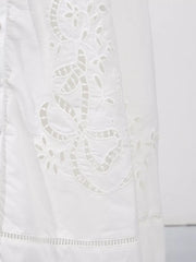 White midi dress with elegant eyelet embroidery and cutout details.