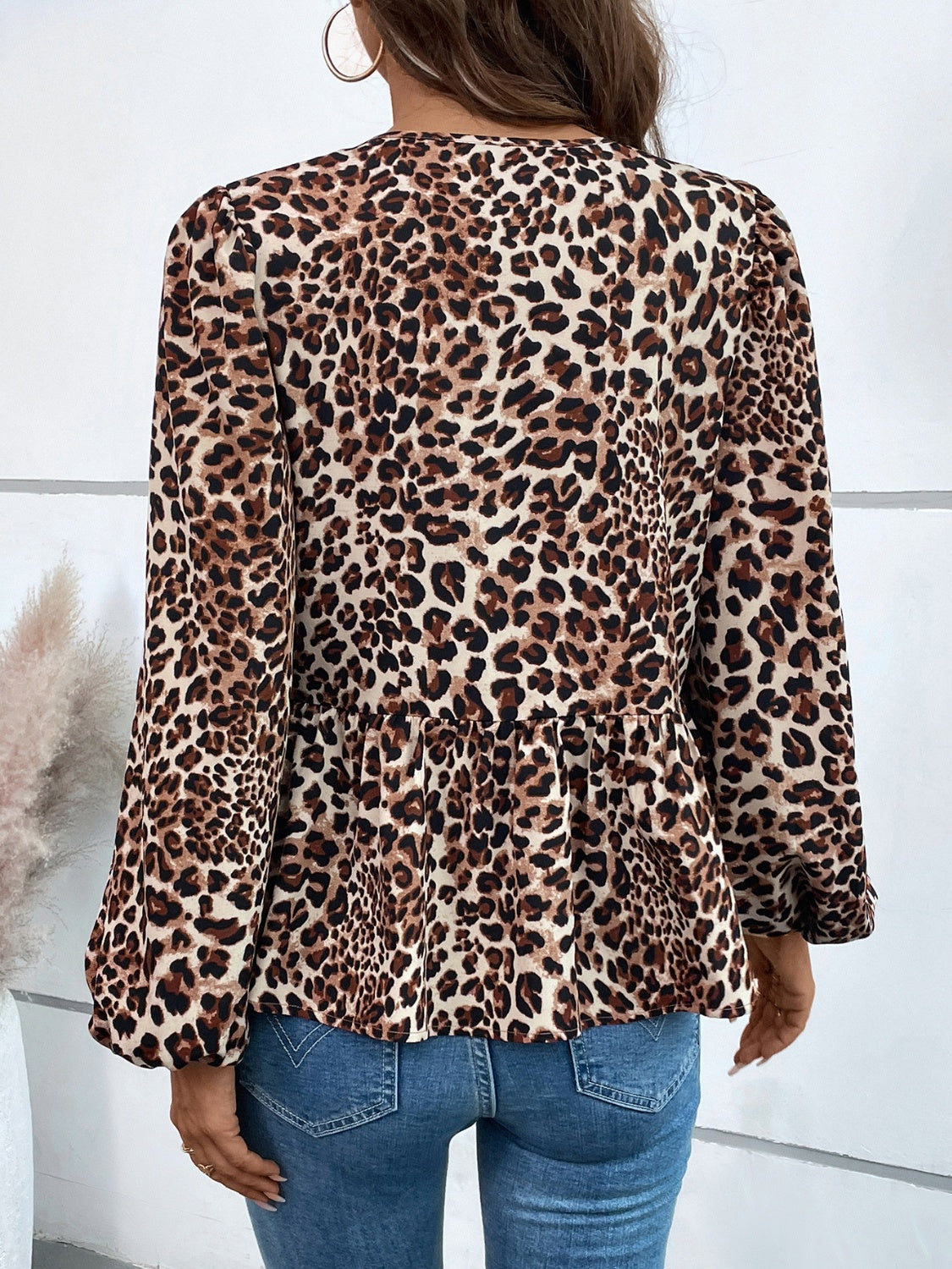 Leopard print peplum blouse with long sleeves and a ruffled hem.