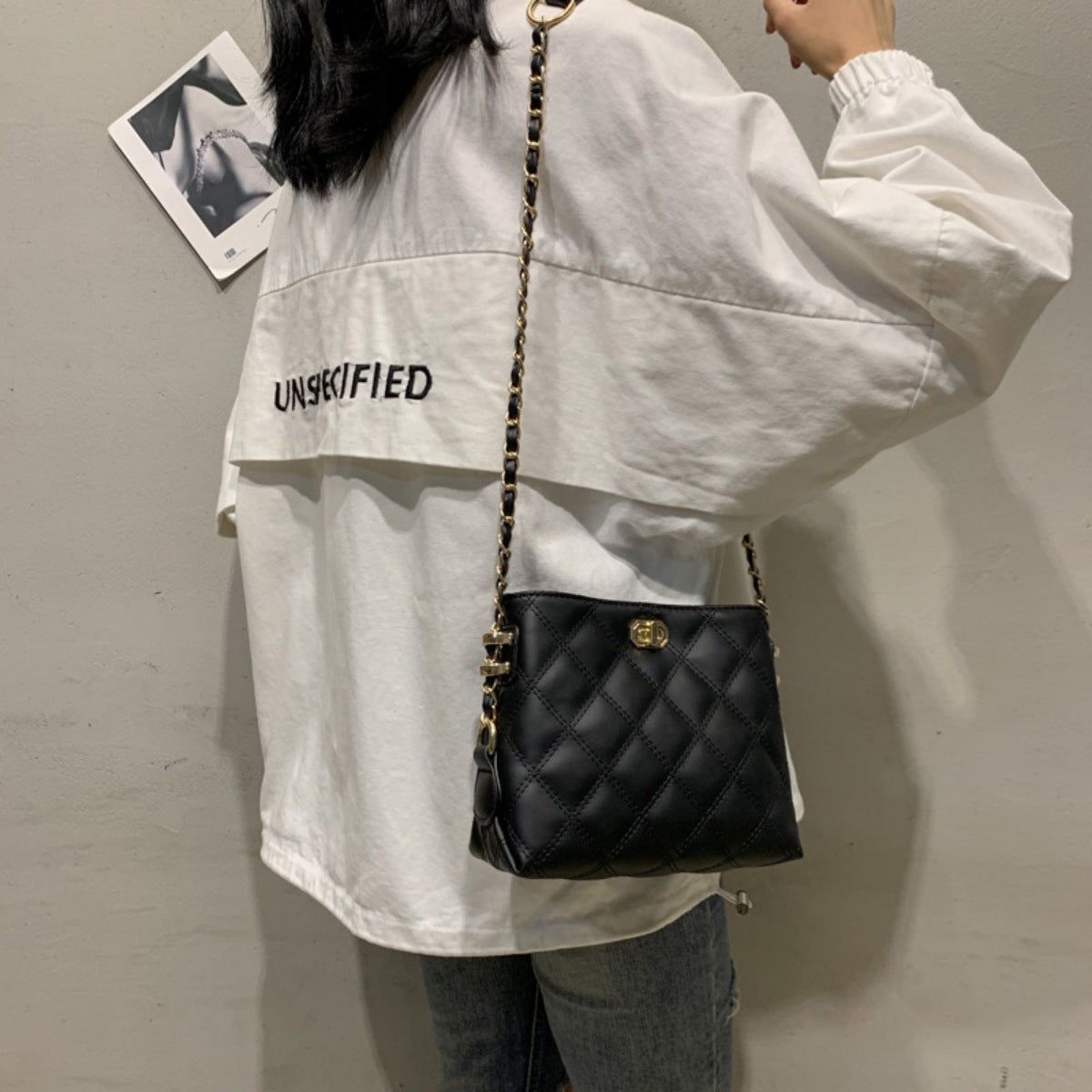 Black quilted crossbody bag with diamond pattern and gold chain strap.