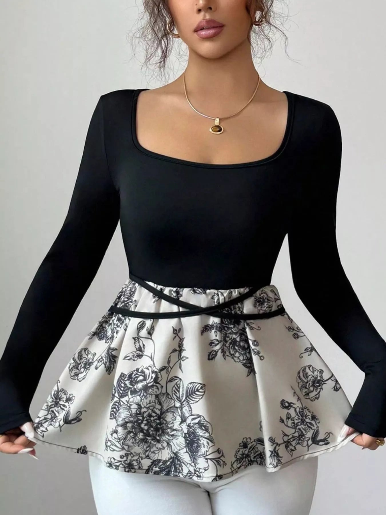 Black long-sleeve top with square neckline and peplum hem featuring a black floral print.