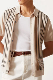Beige knit polo shirt with vertical stripes, buttoned, short sleeves, collared.