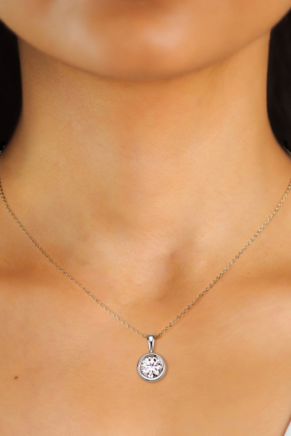 Silver solitaire bezel pendant necklace with a clear stone on a delicate chain.