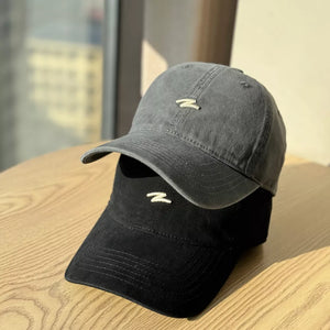 Distressed cotton baseball hats in dark gray and black with embroidered logo detail.