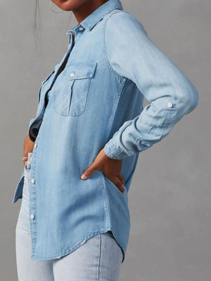 Light blue washed denim utility shirt with buttoned chest pockets and rolled sleeves.