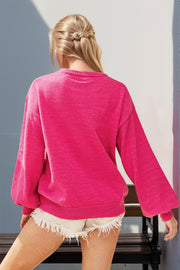 Hot pink knit sweater with balloon sleeves and sequin nutcracker embellishment.