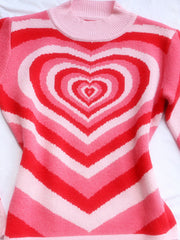 Pink mock neck sweater with concentric heart stripes and ribbed neckline.