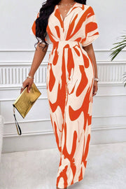 Orange and cream abstract brushstroke wide-leg jumpsuit with V-neck and short sleeves.
