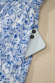 Maxi dress with blue floral print and side pocket holding a phone.