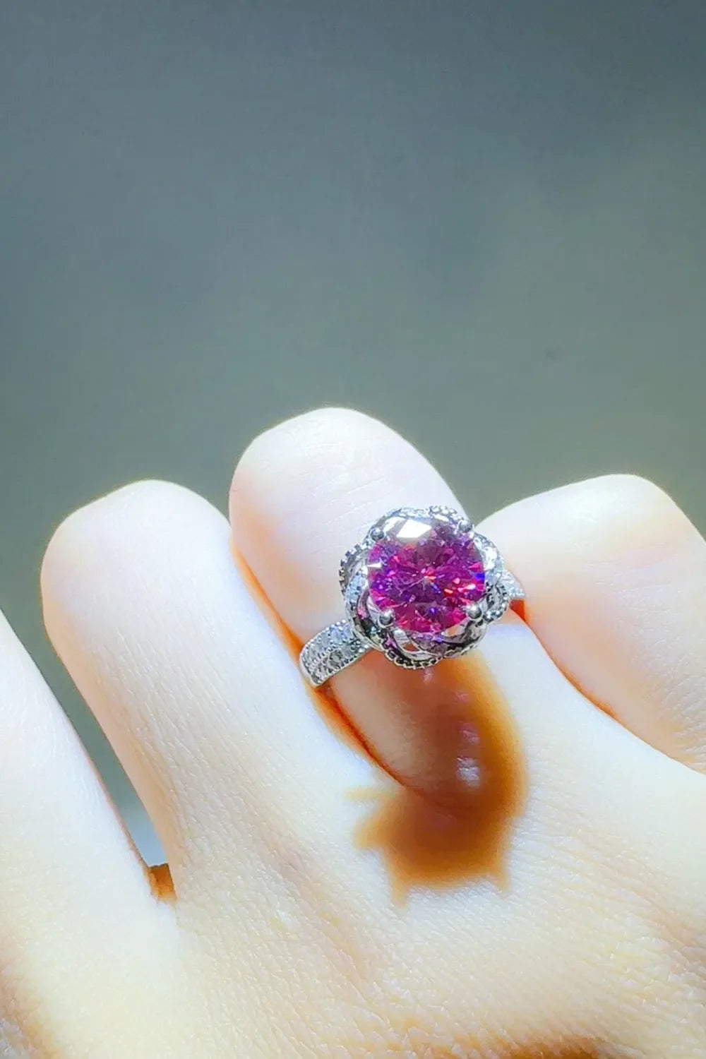 Crimson Bloom moissanite halo ring in cerise with a detailed floral setting and diamond band.