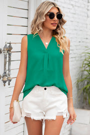 Green textured sleeveless V-neck blouse with front pleats, styled with white distressed shorts.