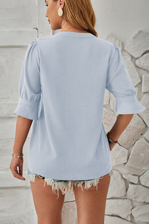 Light blue blouse with puffed sleeves and flared cuffs, basic style.