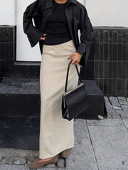 Chic cotton midi skirt in beige with a subtle slit, styled with a black top and shirt.