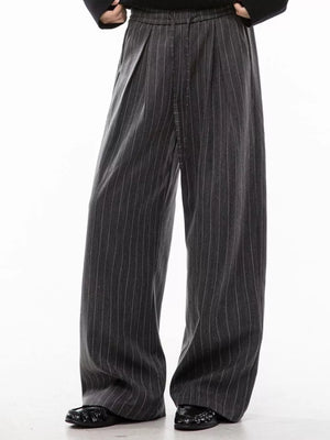 Men's grey pinstripe wide-leg pleated trousers with drawstring waist.
