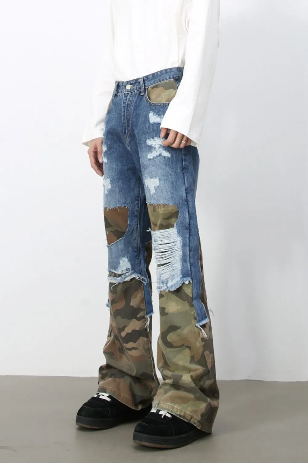 Camouflage patchwork distressed jeans in medium wash denim with baggy fit and frayed hems.