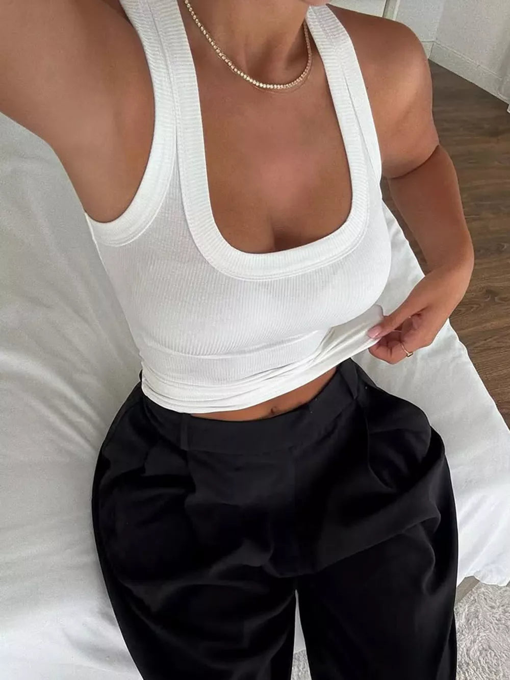 White ribbed halter tank top with deep U-neck, paired with black pants.