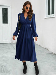 Dark blue tiered midi dress with V-neck, gathered waist, and long puff sleeves.
