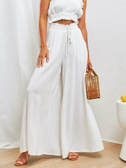 White gathered waist wide-leg palazzo pants with drawstring detail and flowy silhouette.