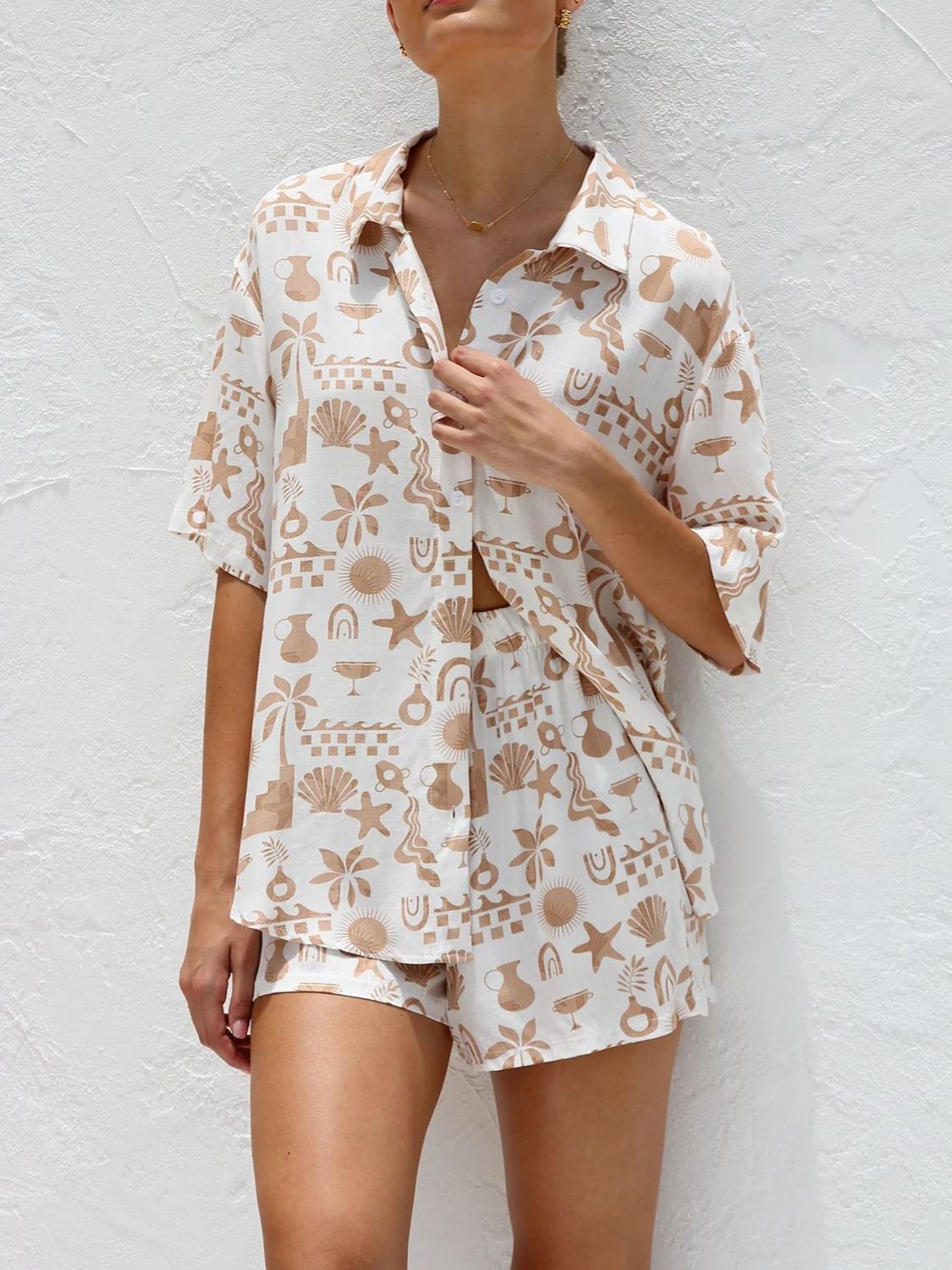 Tan and white resort set with beach graphic print, button-up short sleeve shirt and shorts.