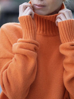 Orange ribbed turtleneck sweater with relaxed fit and cuffed sleeves.