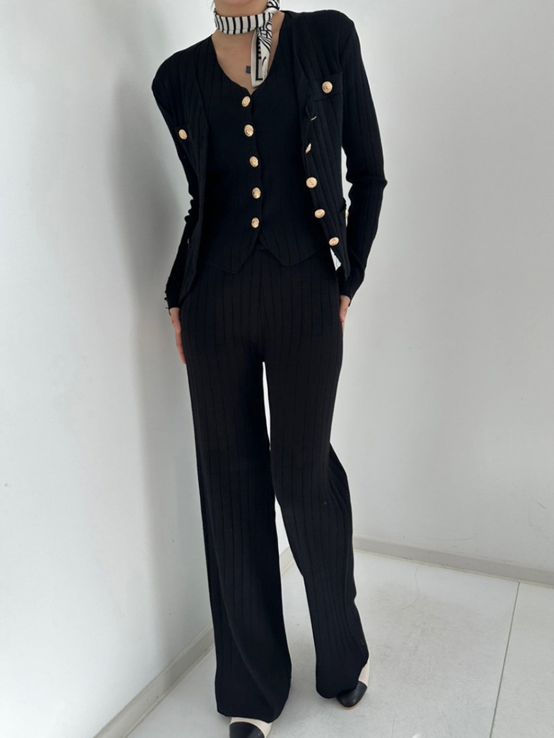 Black ribbed knit outfit set with gold buttons, featuring a cardigan and wide-leg pants.