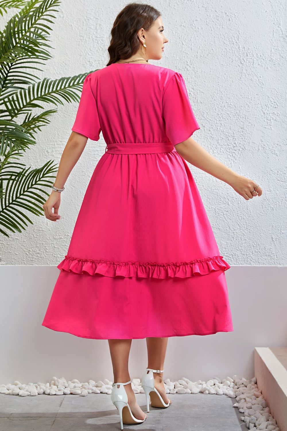 Hot pink wrap-front midi dress with tiered ruffled hem and belted waist.