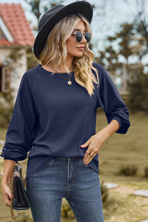 Dark blue waffle knit eyelet raglan sleeve top with crew neck and cuffed sleeves.