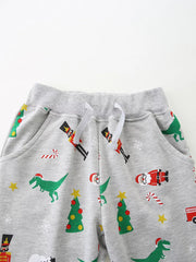 Children's gray cotton pajama pants with a fun Christmas print featuring dinosaurs, Santa, nutcrackers, and trees.