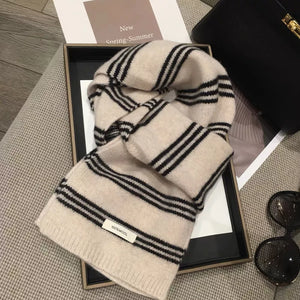Off-white wool knit scarf with black stripes and a 100% wool tag.