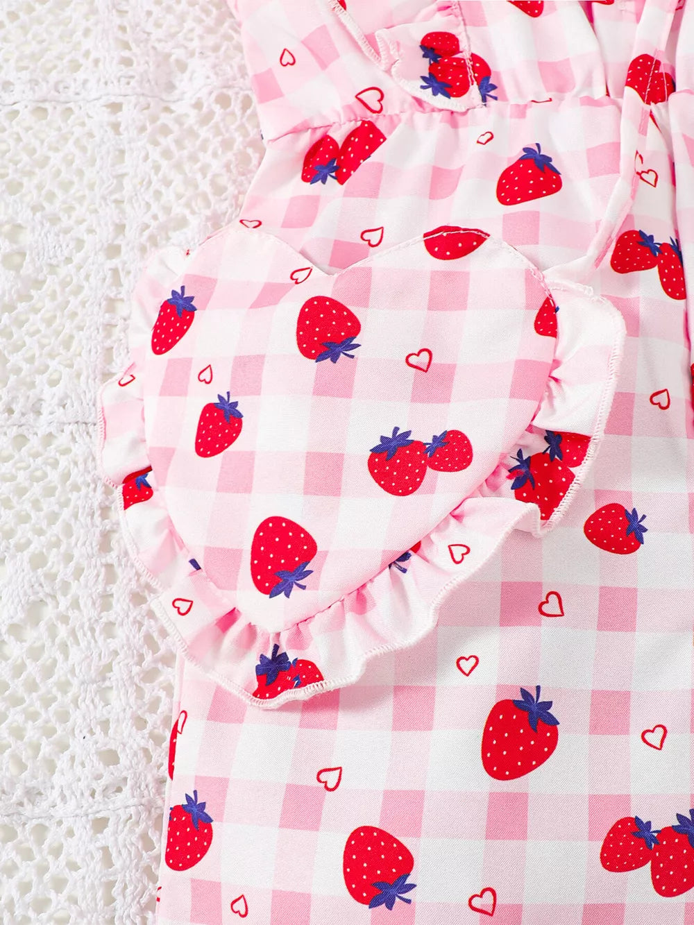 Strawberry ruffle jumpsuit with heart detail and gingham pattern.
