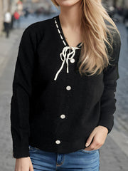 Black knit cardigan with ribbon tie, white contrast stitching and pearl buttons.